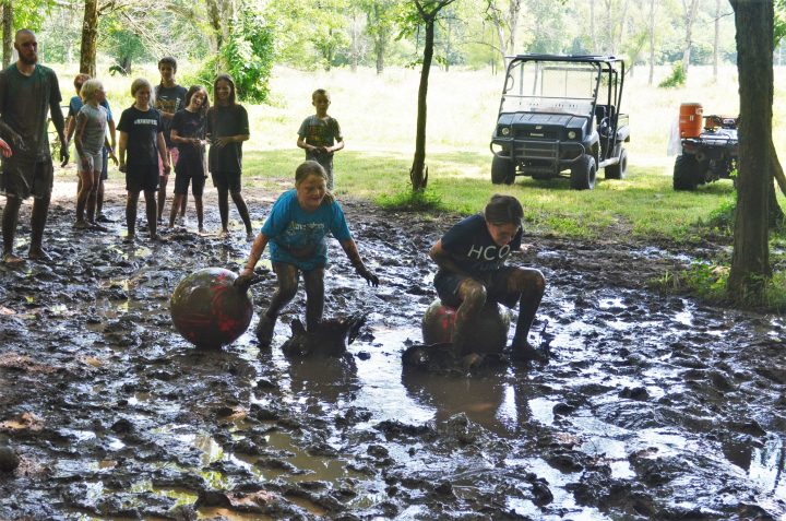 Image of two campers jumping on bouncy balls in the mud