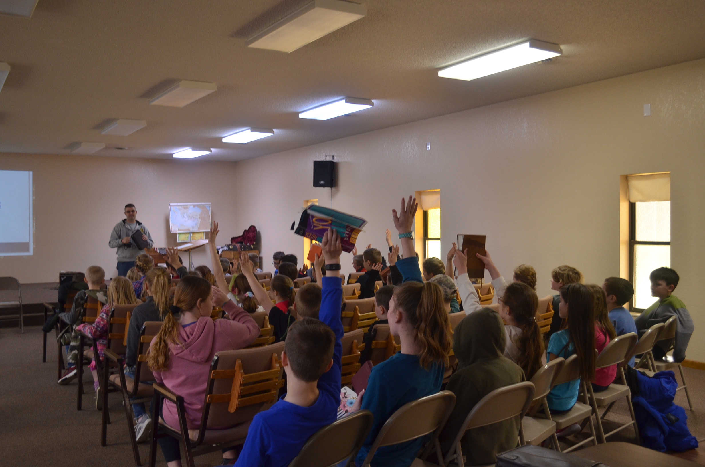 Image of kids raising up their Bibles in chapel